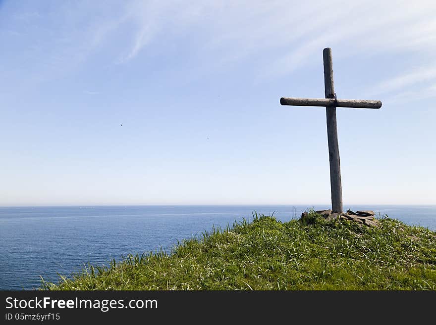 The cross on the rock over the sea meets floating ships