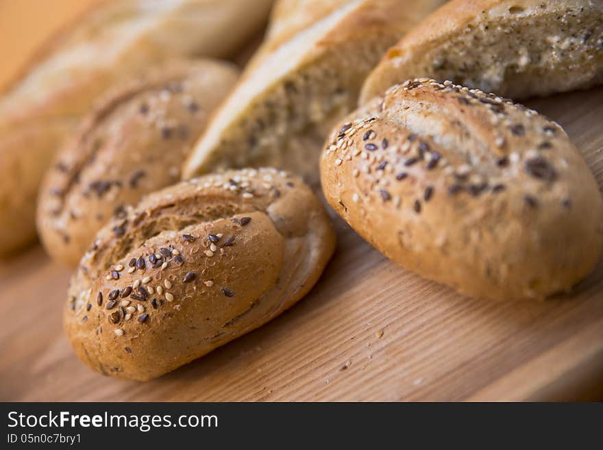 Rolls with sesame seeds over wooden cutting board background. Selective focus. Rolls with sesame seeds over wooden cutting board background. Selective focus.