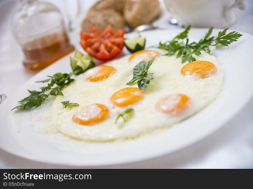 Colorful breakfast - fried eggs with beautiful yellow yolks, tomato, cucumbers, green parsley and mint. Selective focus. Colorful breakfast - fried eggs with beautiful yellow yolks, tomato, cucumbers, green parsley and mint. Selective focus.