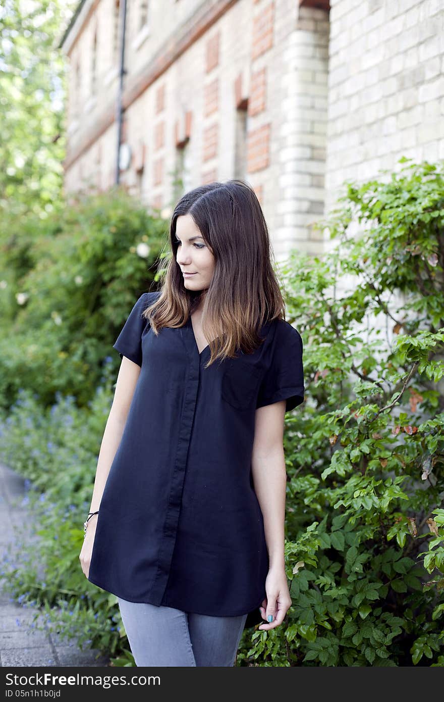 Pretty girl standing in the park, girl with brown hair wearing black shirt. Pretty girl standing in the park, girl with brown hair wearing black shirt