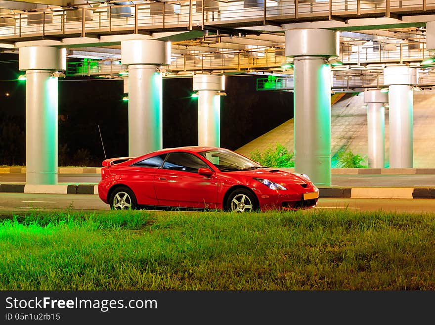 Red sport car under the brige with lights.