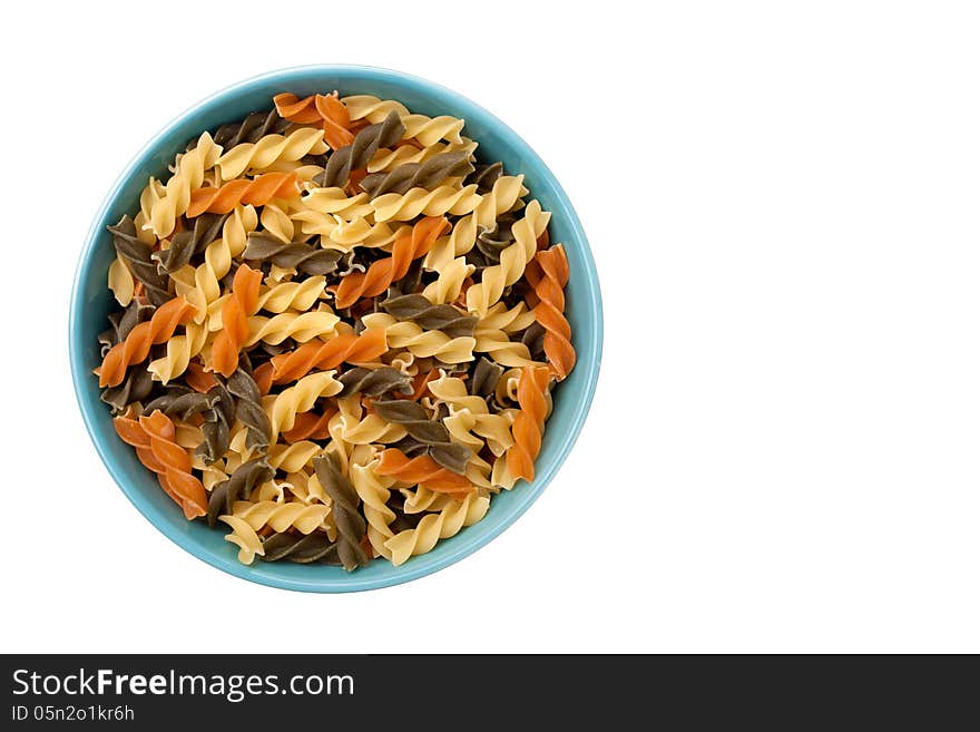 Colorful raw fusilli in blue bowl isolated on white background. Colorful raw fusilli in blue bowl isolated on white background