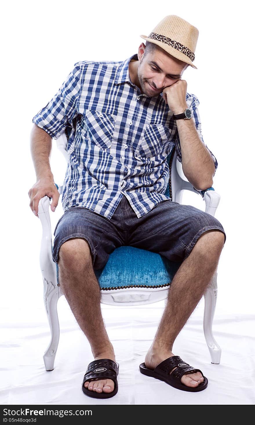 Bored tourist in hat and blue shirt, sitting in a chair and waiting for something. Isolated on white background. Bored tourist in hat and blue shirt, sitting in a chair and waiting for something. Isolated on white background.