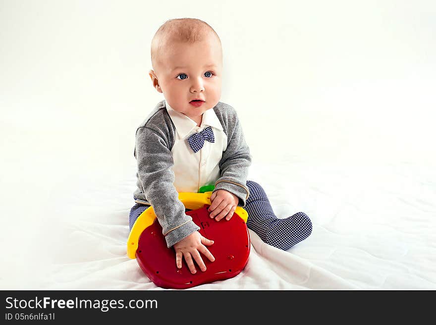 The small boy plays with a red toy