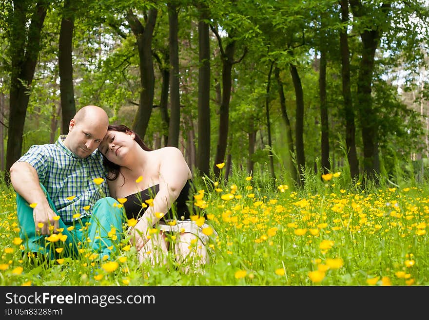 Happy young couple is sitting in a field of buttercups. Happy young couple is sitting in a field of buttercups