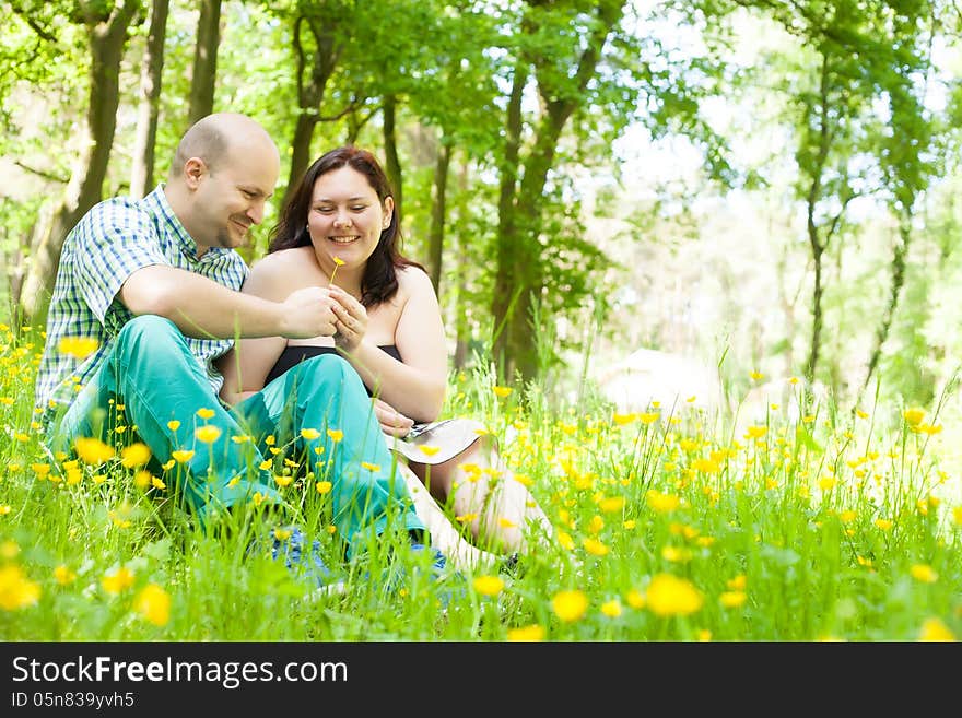 Happy young couple is sitting in a field of buttercups. Happy young couple is sitting in a field of buttercups