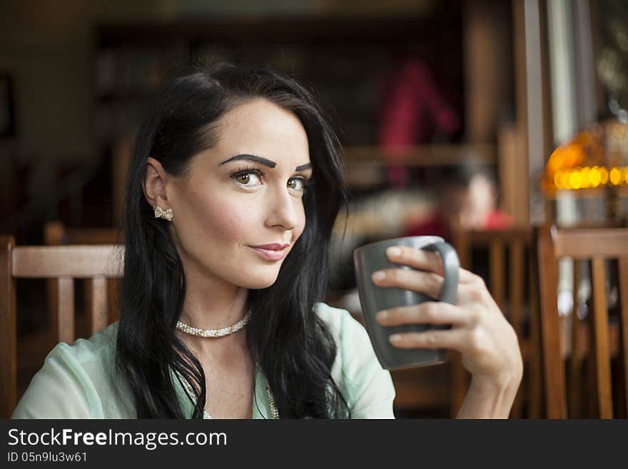 Beautiful young woman with dark brown hair and eyes holding a gray coffee cup. Beautiful young woman with dark brown hair and eyes holding a gray coffee cup.