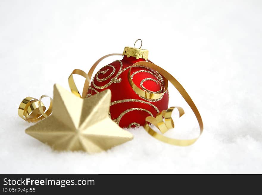 Red-golden bauble with the ribbon on the snow. Red-golden bauble with the ribbon on the snow