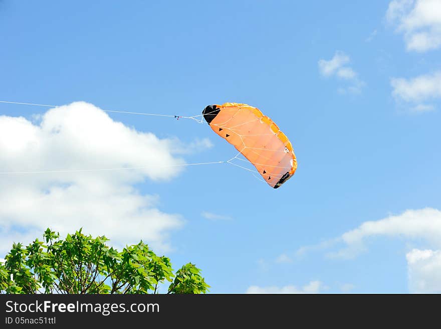 Kite flying on background of blue sky with clouds.