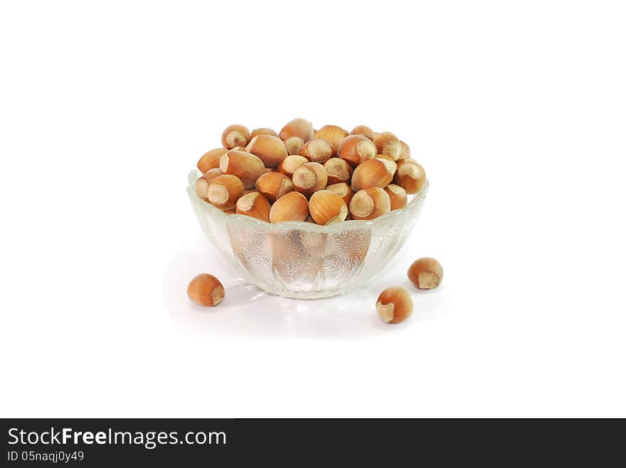 A small glass vase filled with hazelnuts. A small glass vase filled with hazelnuts