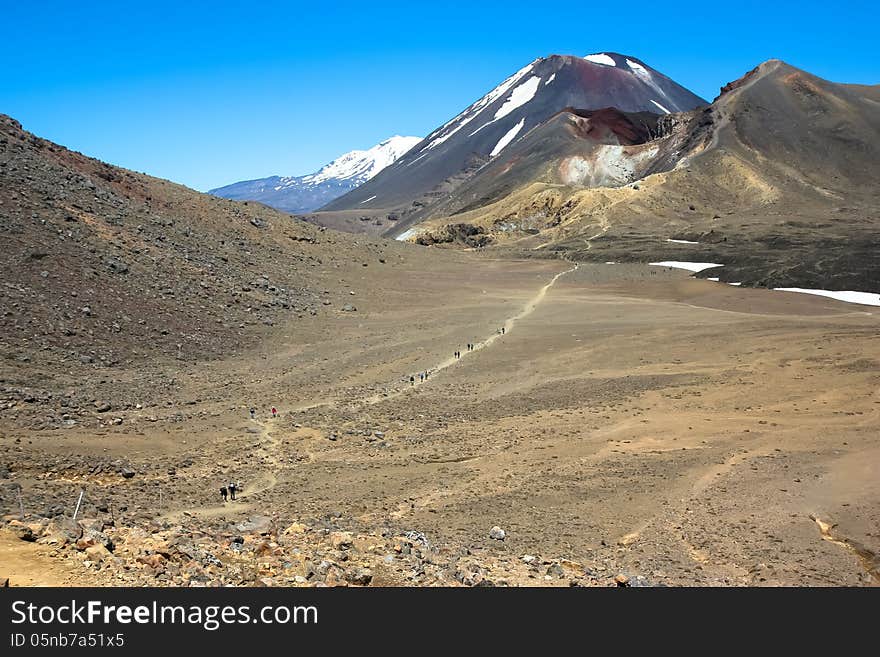 Hikers trek across the lunar, Martian landscape, heading for Mount Ngauruhoe/. Hikers trek across the lunar, Martian landscape, heading for Mount Ngauruhoe/