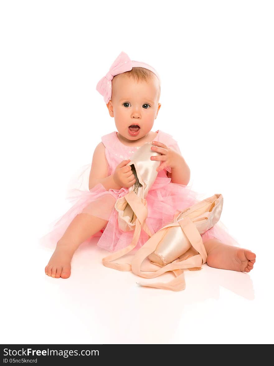 Little baby girl in a pink ballerina dress with pointe shoes isolated on a white background