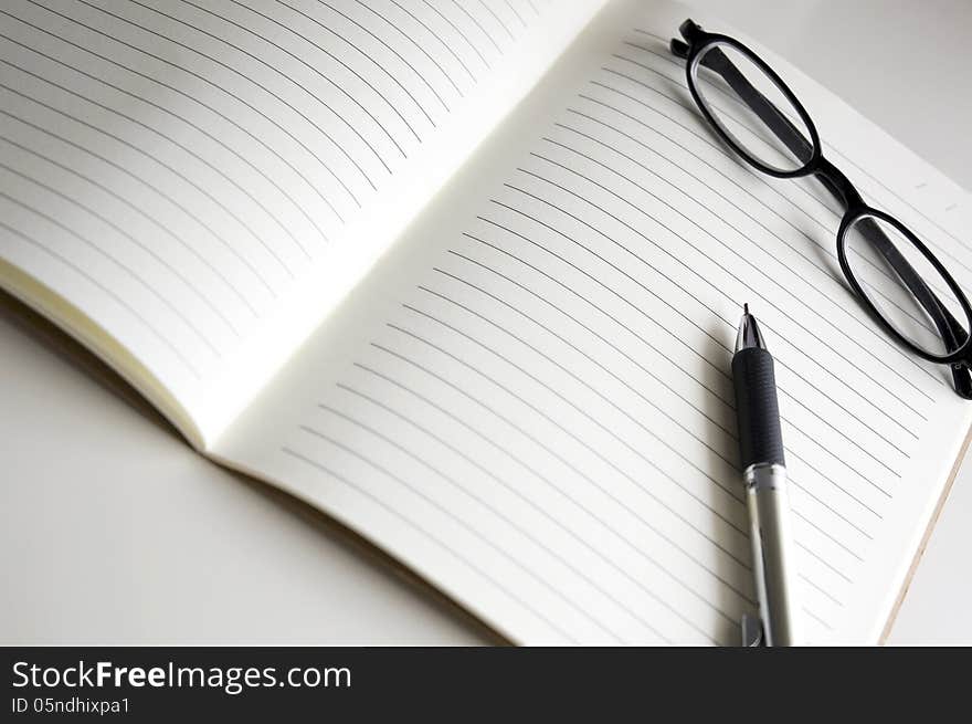 Blank notebook pages with pen and glasses