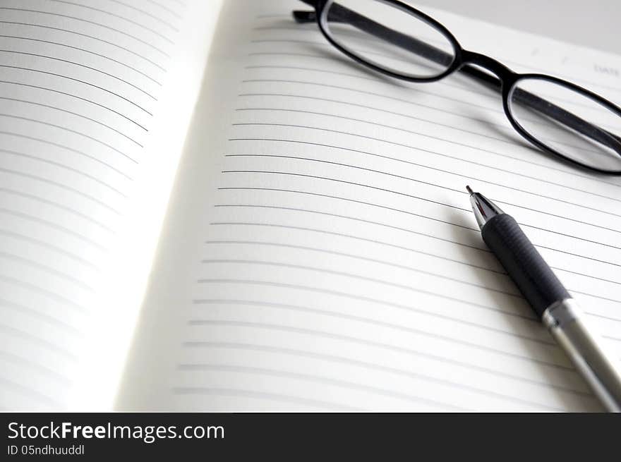 Open notebook with pen and glasses