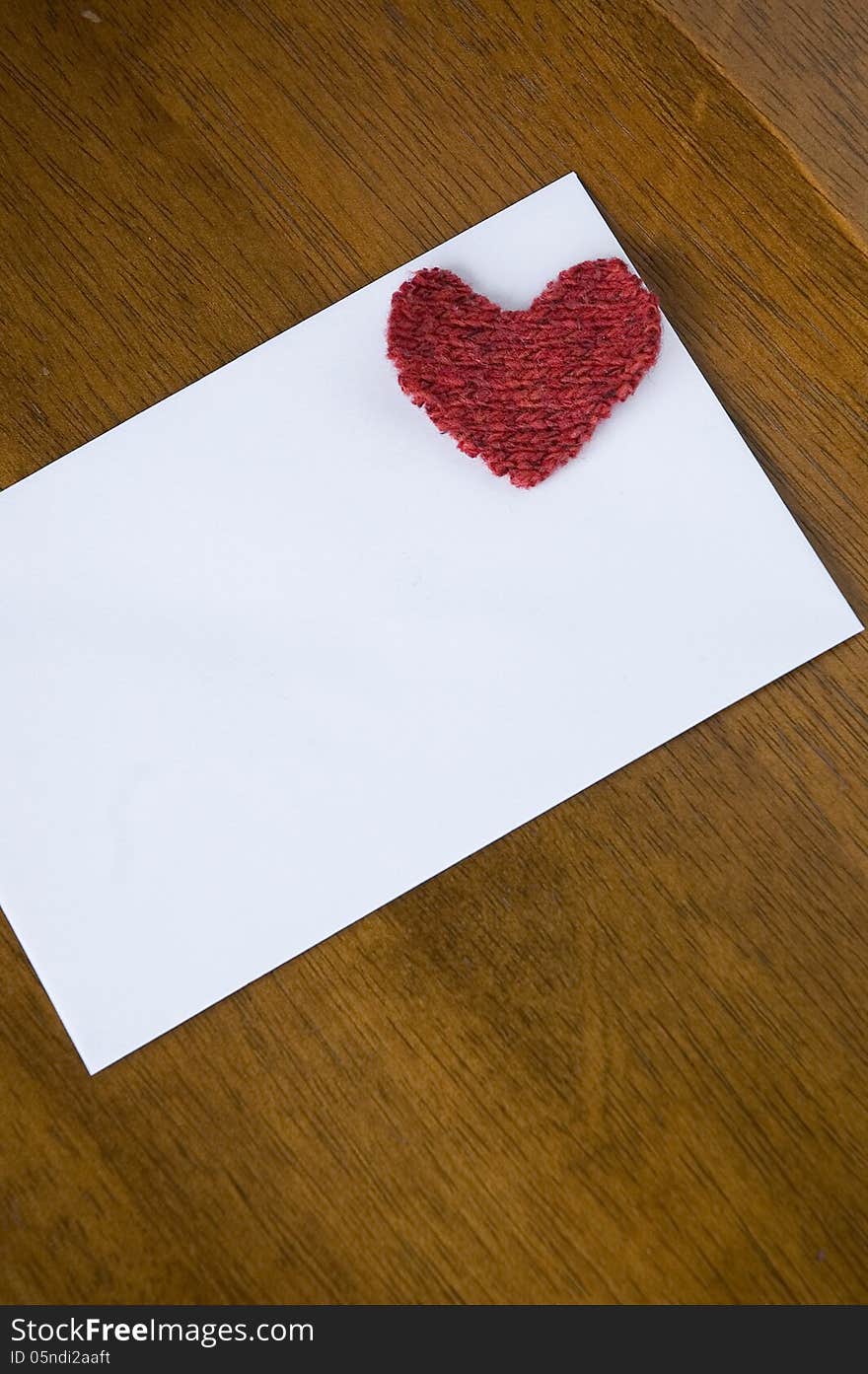 White card with red heart on wooden table