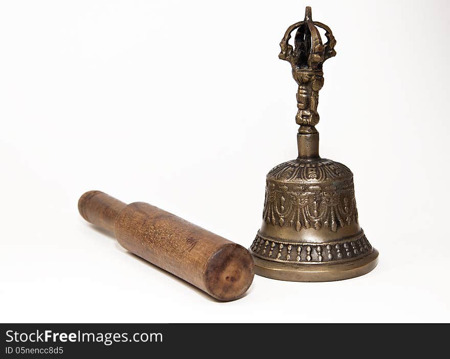 Traditional Buddhist bell and wooden playing stick against a white background. The bell represents the female aspect of wisdom. A universal sound is created when the wooden stick is rubbed around the outer circumference of the bell. Traditional Buddhist bell and wooden playing stick against a white background. The bell represents the female aspect of wisdom. A universal sound is created when the wooden stick is rubbed around the outer circumference of the bell.