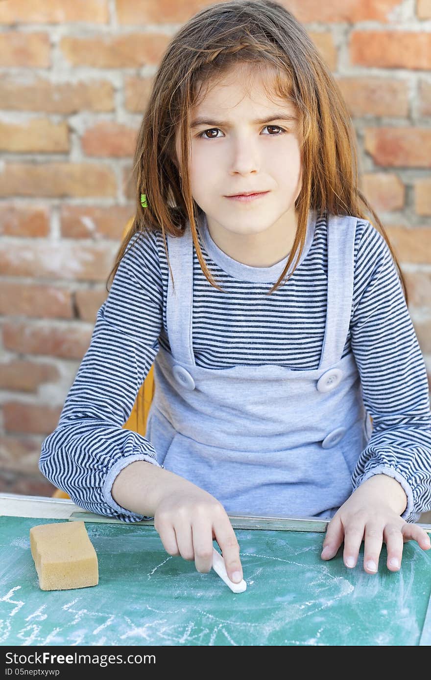 Little girl writing on blackboard