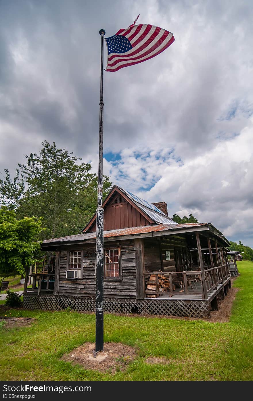 Old log cabin and american flag flying over on a pole