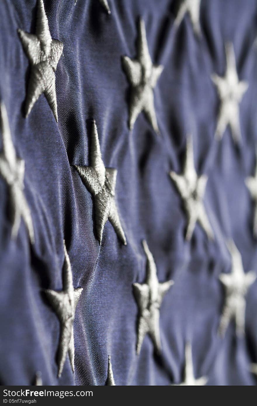 Horizontal close up Shot of American flag focused on the white stars in blue field side lit with shadows. Horizontal close up Shot of American flag focused on the white stars in blue field side lit with shadows