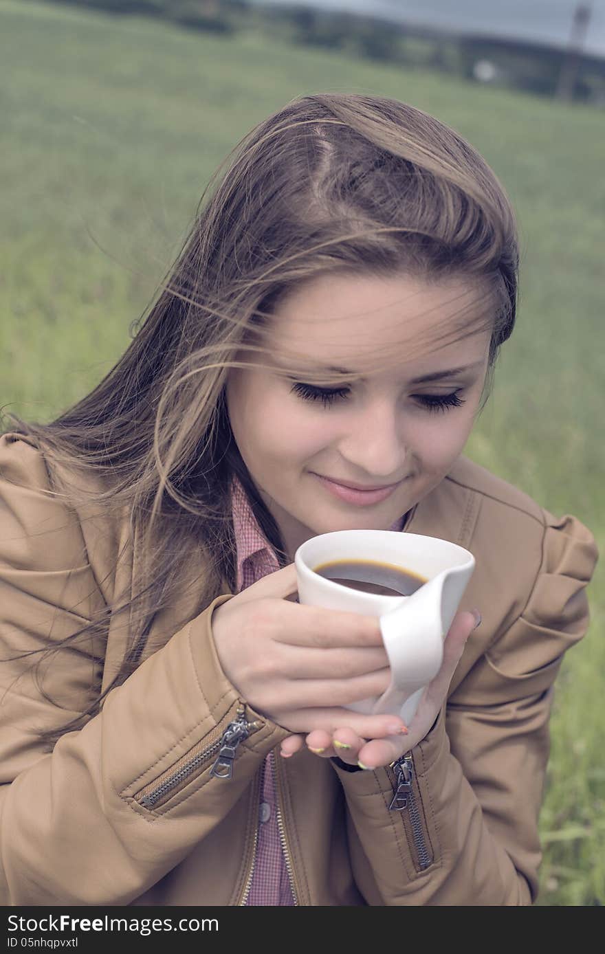 Girl drinks coffee with pleasure outdoors