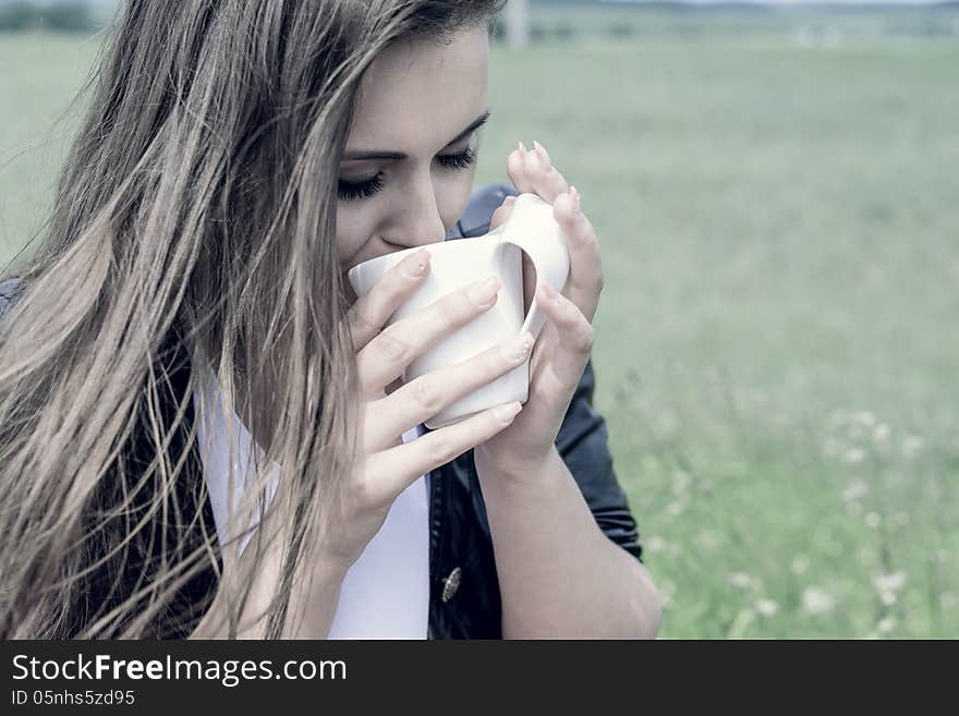 Girl drinks coffee with pleasure outdoors