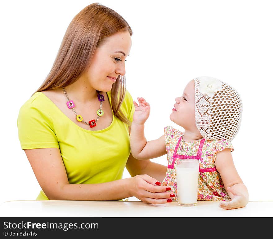 Mother giving milk glass to little girl sitting at table isolated on white