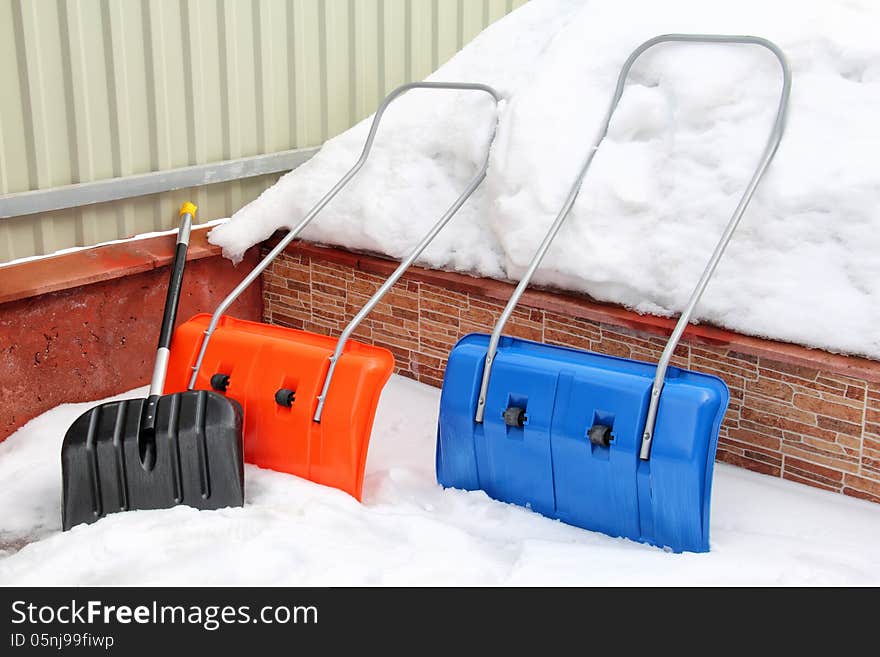 Three snow shovels are on a snow pile in winter