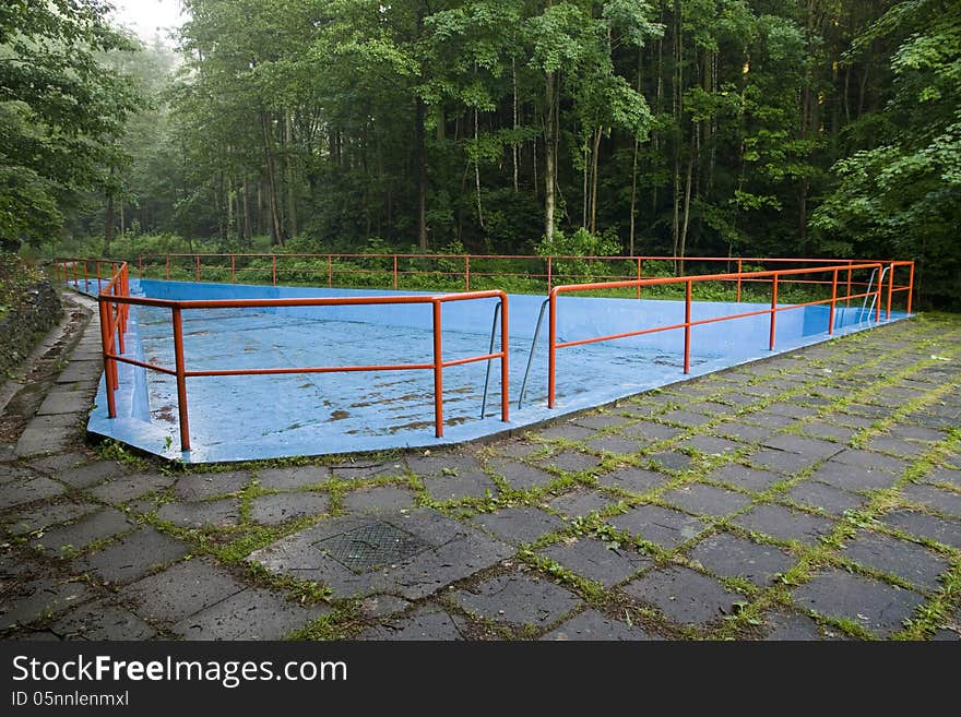 Drained pool blue with red railings, swimming pool in the middle of the forest