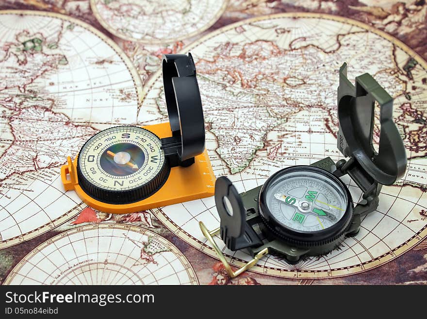 Two compass lie on the background of the map of the world. Two compass lie on the background of the map of the world