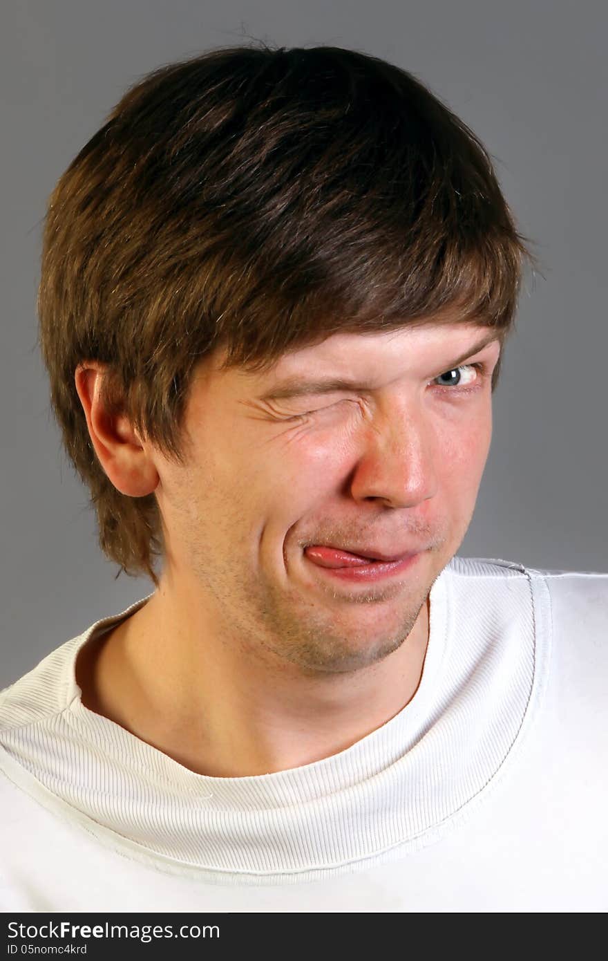 Close up portrait of winking man shows tongue . Gray background. Close up portrait of winking man shows tongue . Gray background