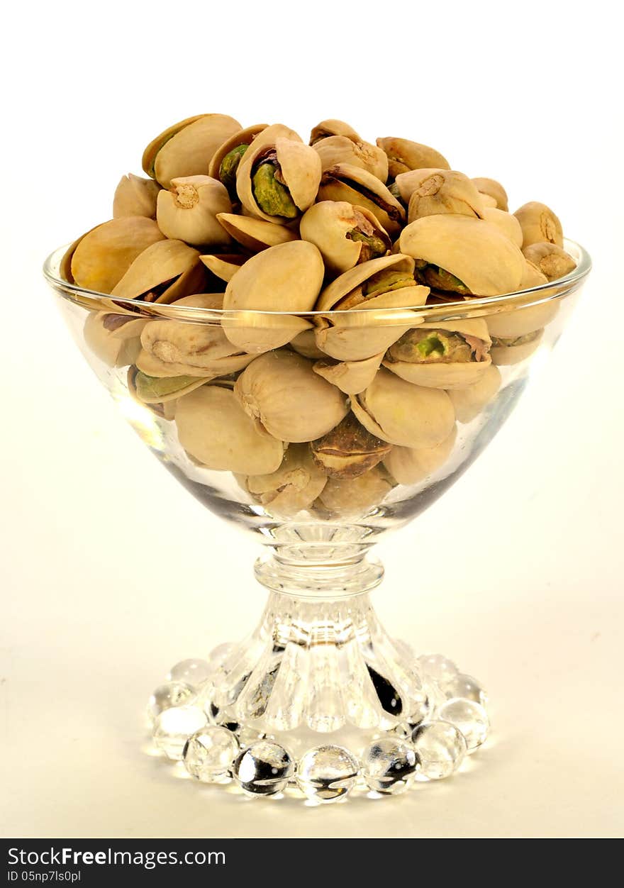 A small glass bowl of pistashios in the shell.