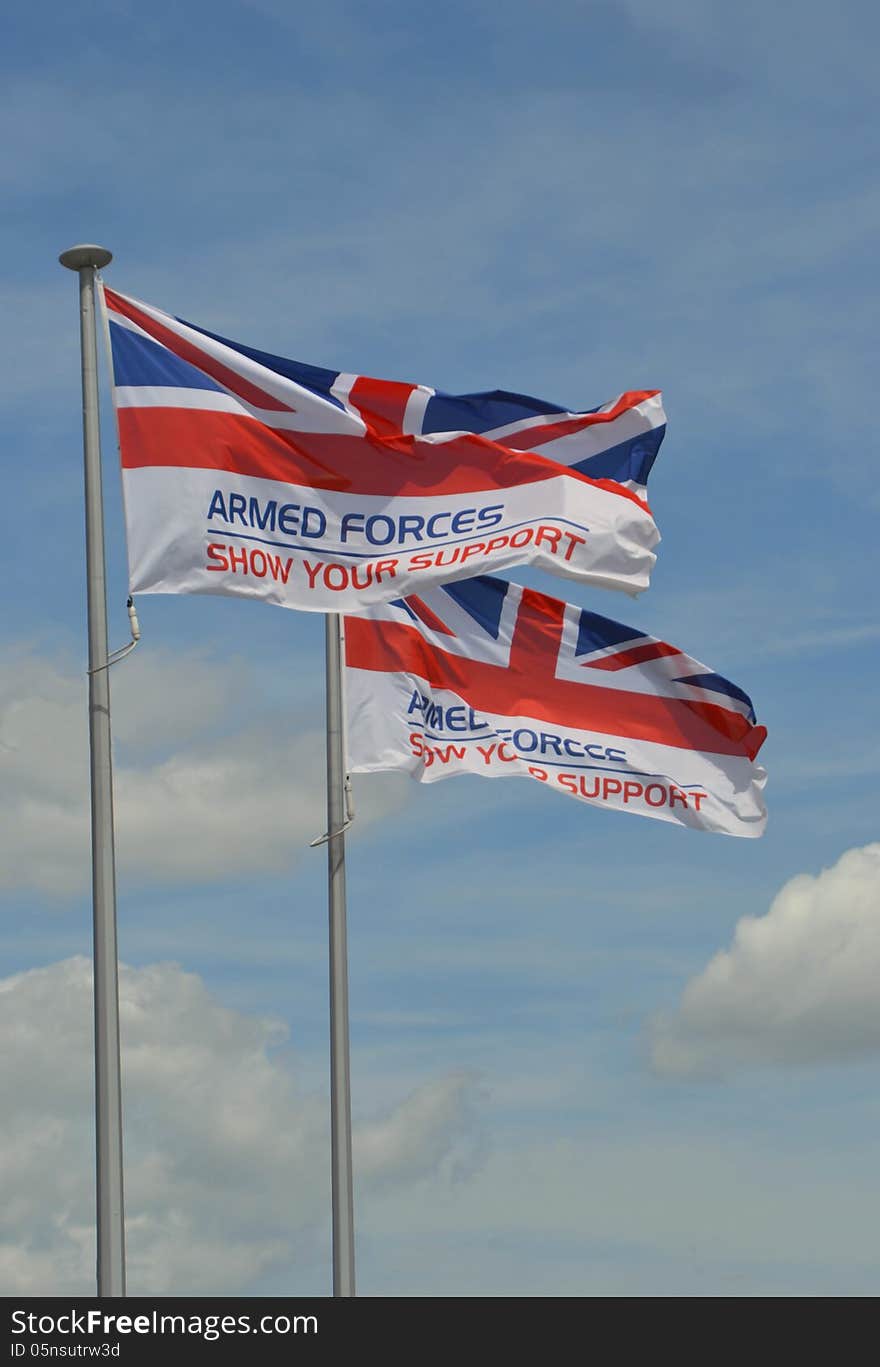 Two Union Jack flags with the words armed forces show your support flying in the wind, on a cloudy summers day background. Two Union Jack flags with the words armed forces show your support flying in the wind, on a cloudy summers day background