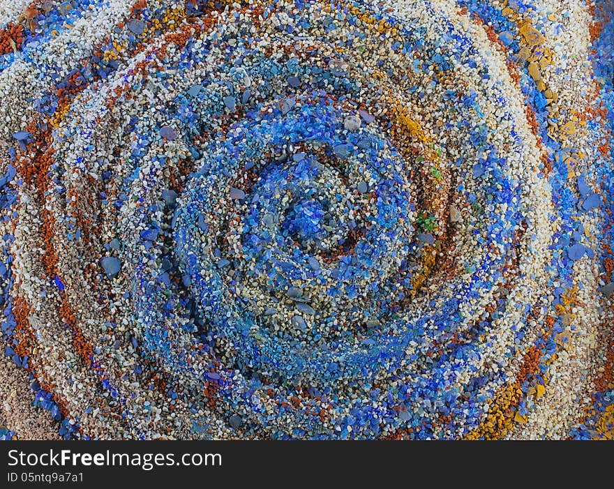 Close up on an abstract whirpool composition made by multicolored sand