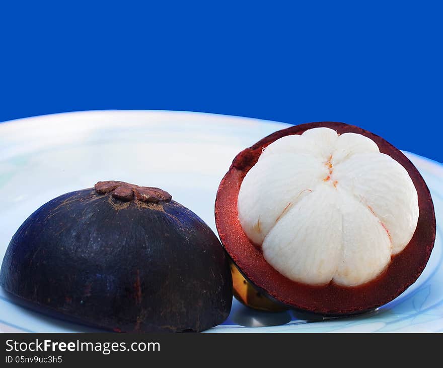 A mangosteen is half-cut to show its white flesh.