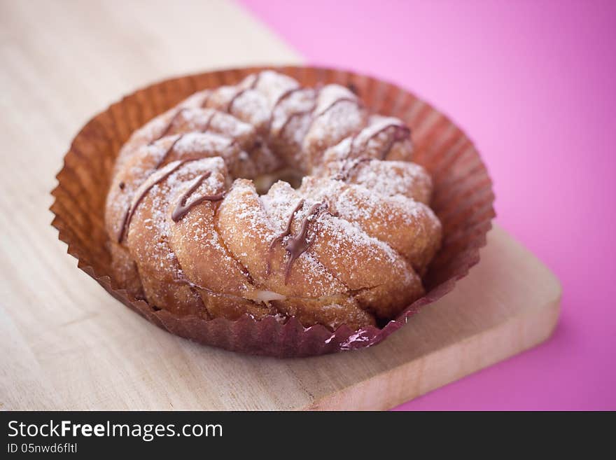 Donut on pink background, on wood