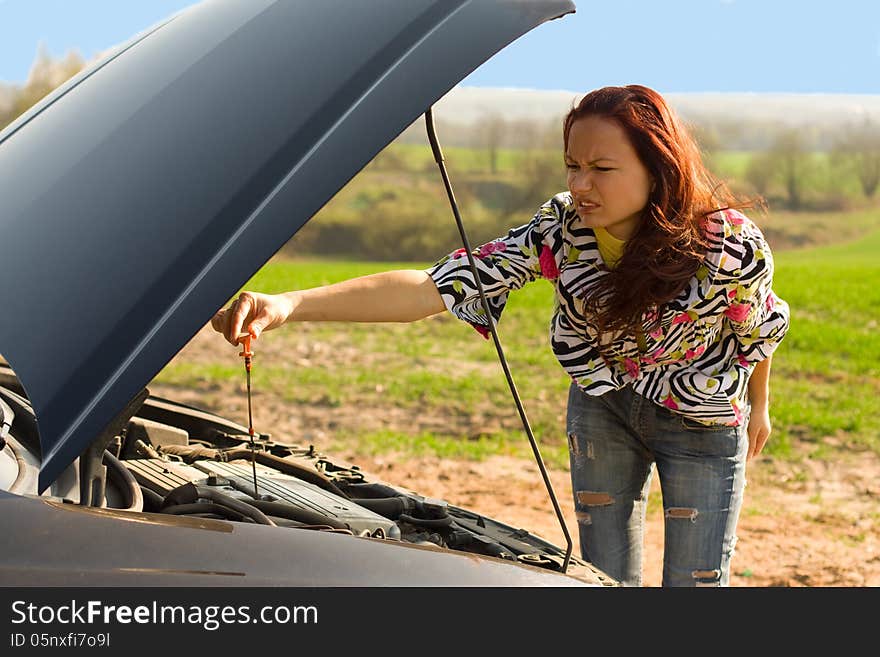 Young woman bent over car engine