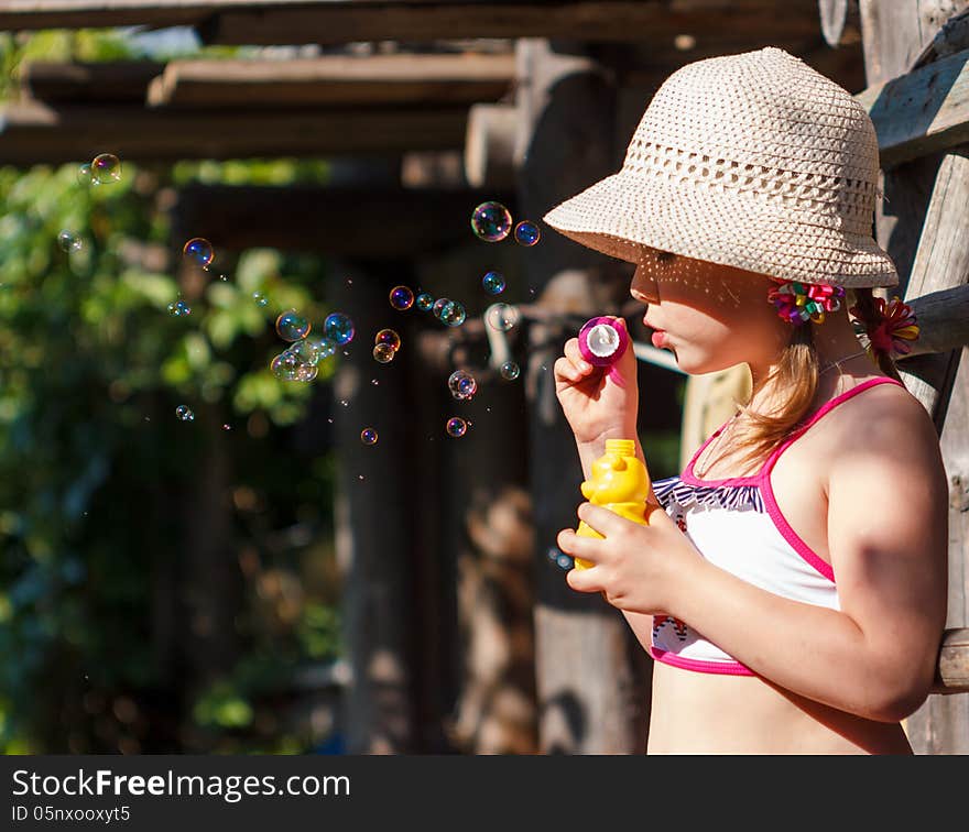 Little girl in a hat blowing soap bubbles. Little girl in a hat blowing soap bubbles