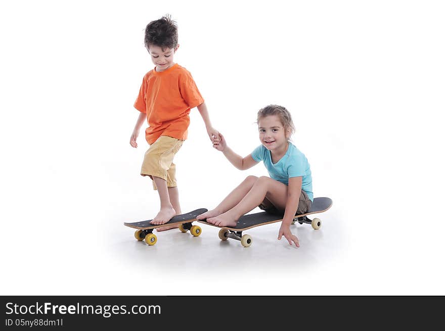 Photography of preschool boy and girl ridding skate board in a studio on white background. Photography of preschool boy and girl ridding skate board in a studio on white background