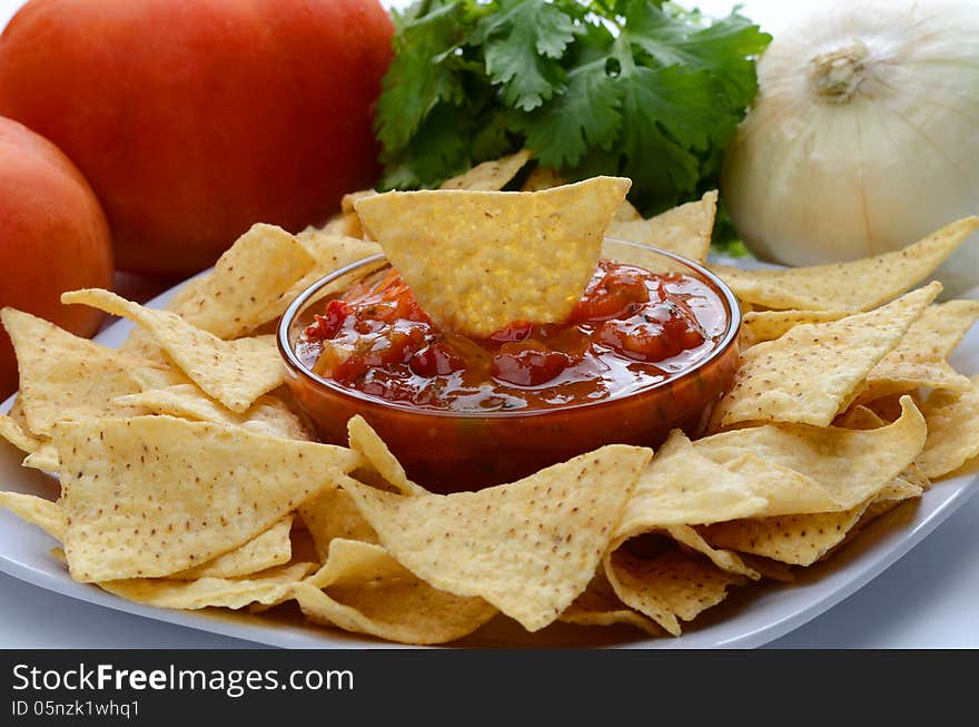 A Plate of chips and salsa with onion, cilantro and tomatoes