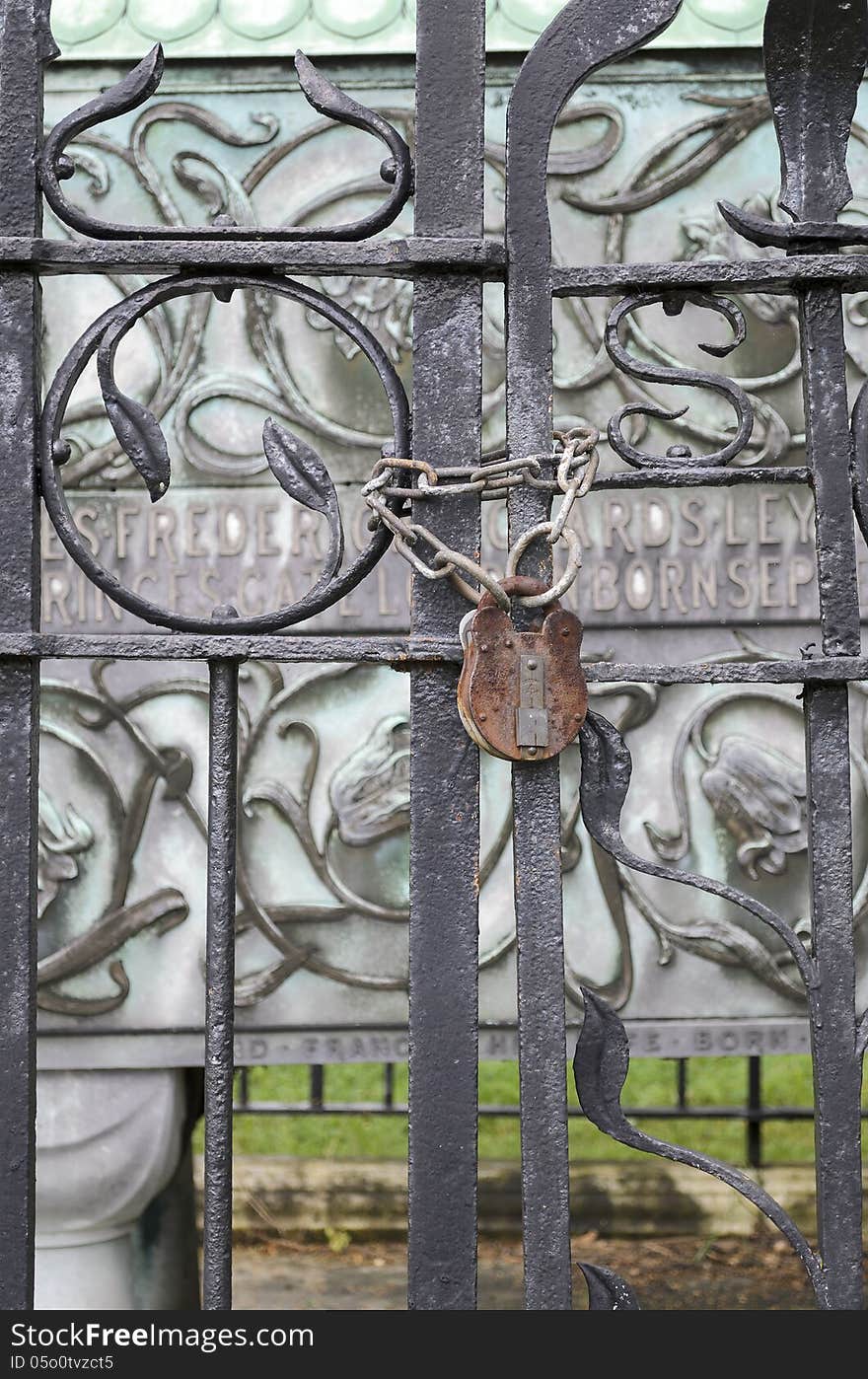 An iron gate is closed by a heavy duty padlock rusty.