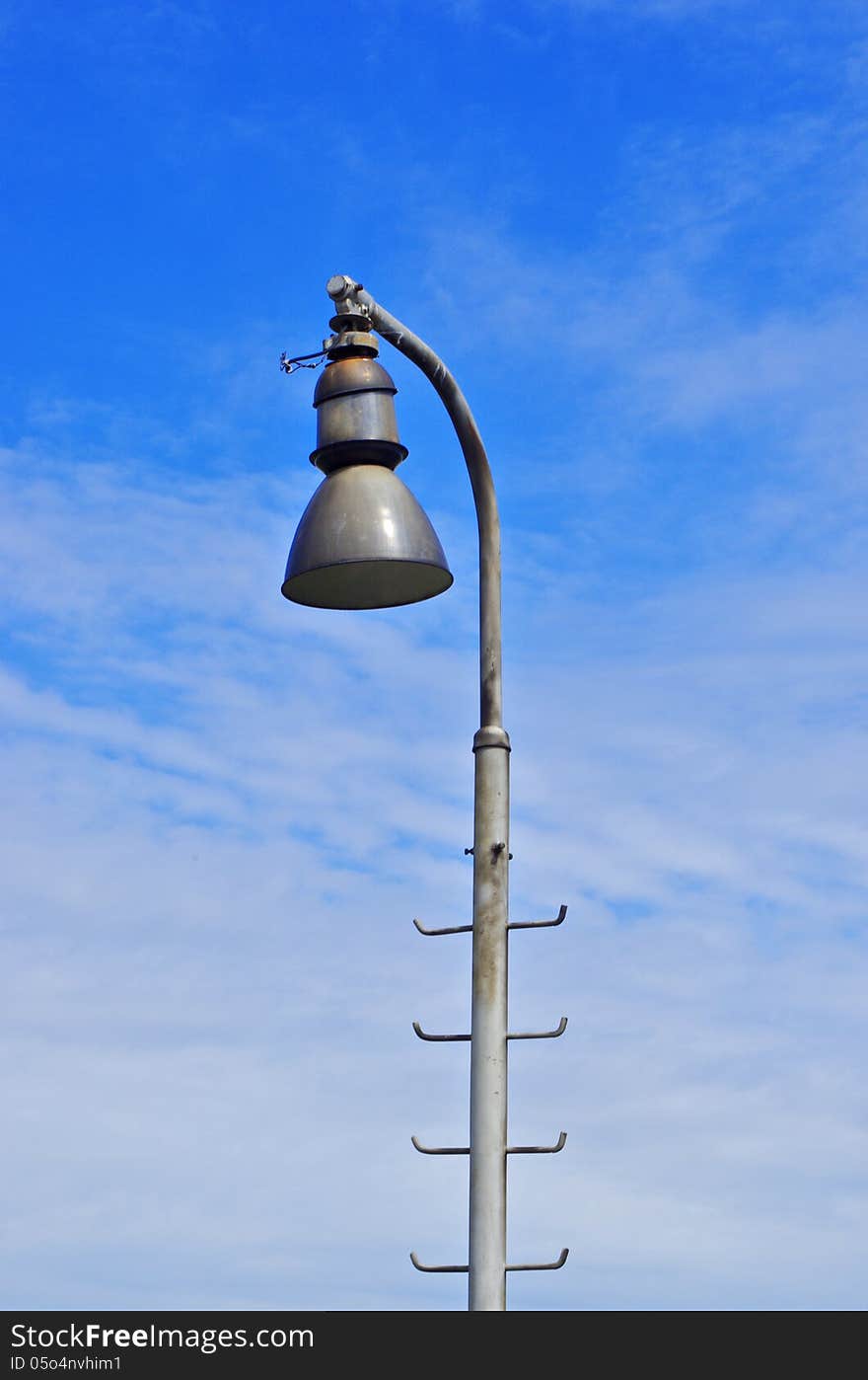 One lamp on railway track and blue sky on the background. One lamp on railway track and blue sky on the background