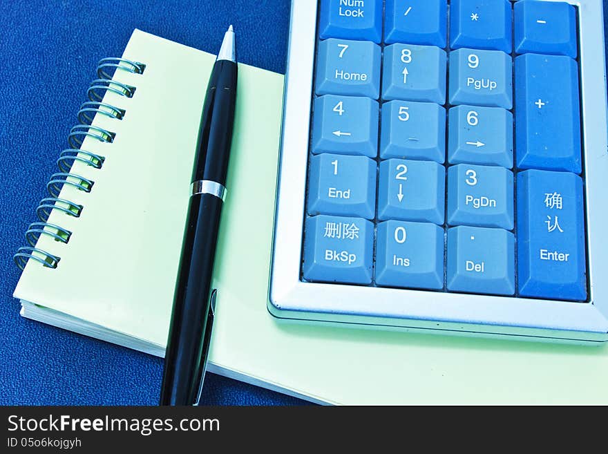 Calculator and pen on blank notebook. Shot on background