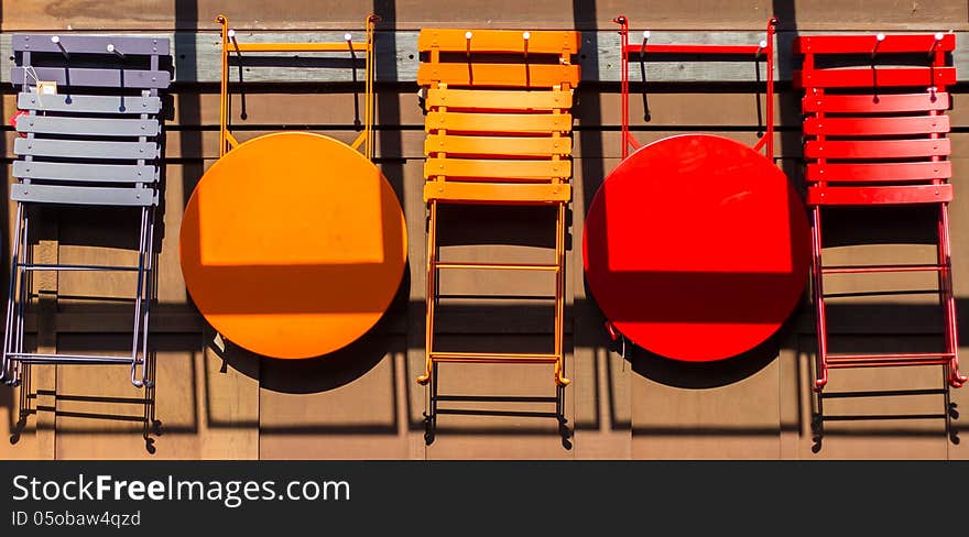 Different colored chairs and tables hanging on the wall.