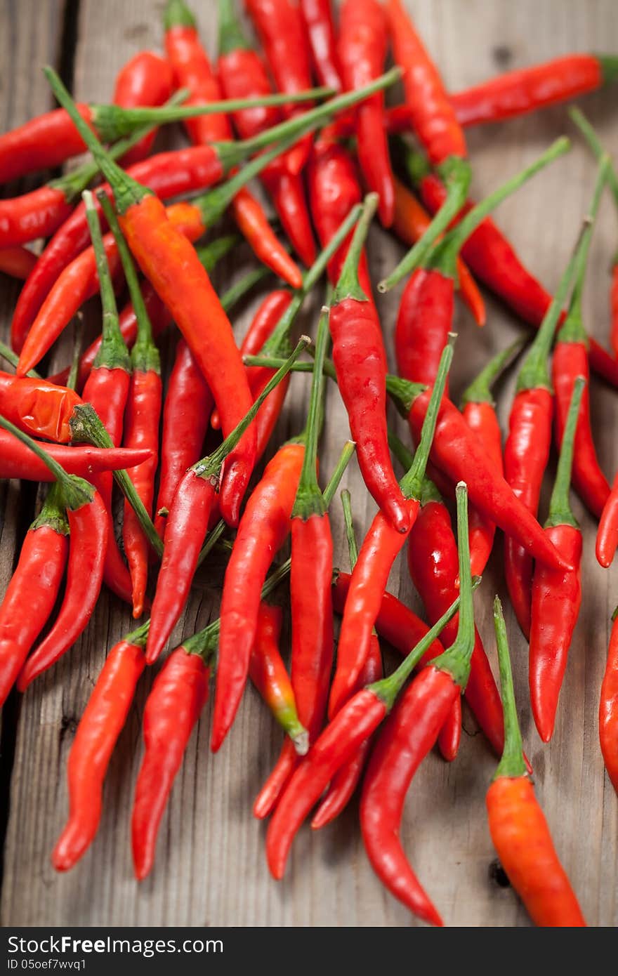 The pods of red chili peppers on a wooden background. The pods of red chili peppers on a wooden background