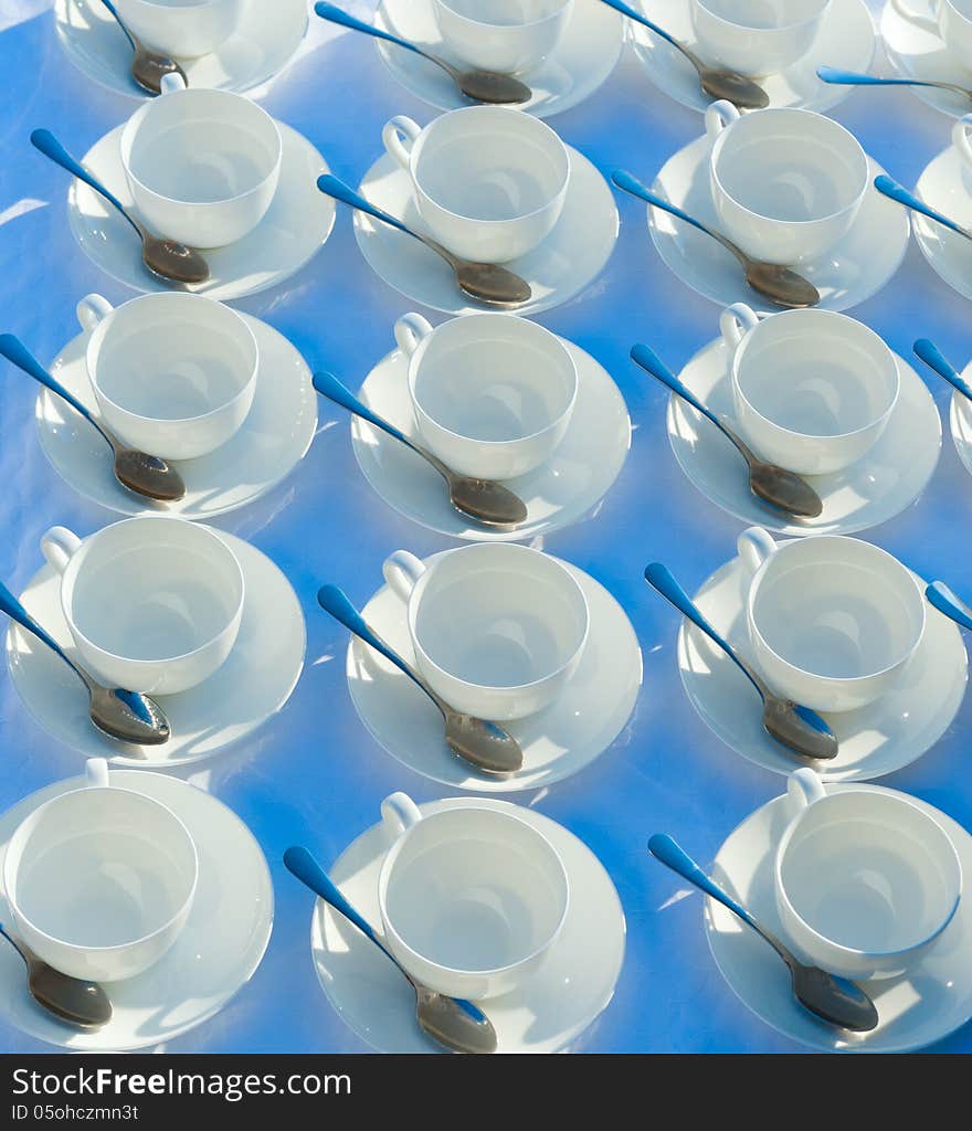 Stacked empty teacups with teaspoons at a function over white ba