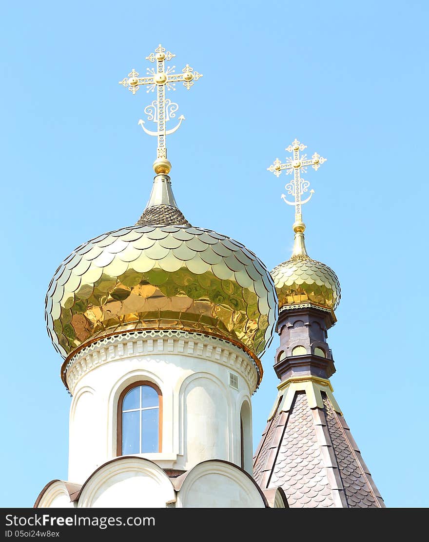 Golden dome of the Orthodox church on the blue sky background partially covered with snow.