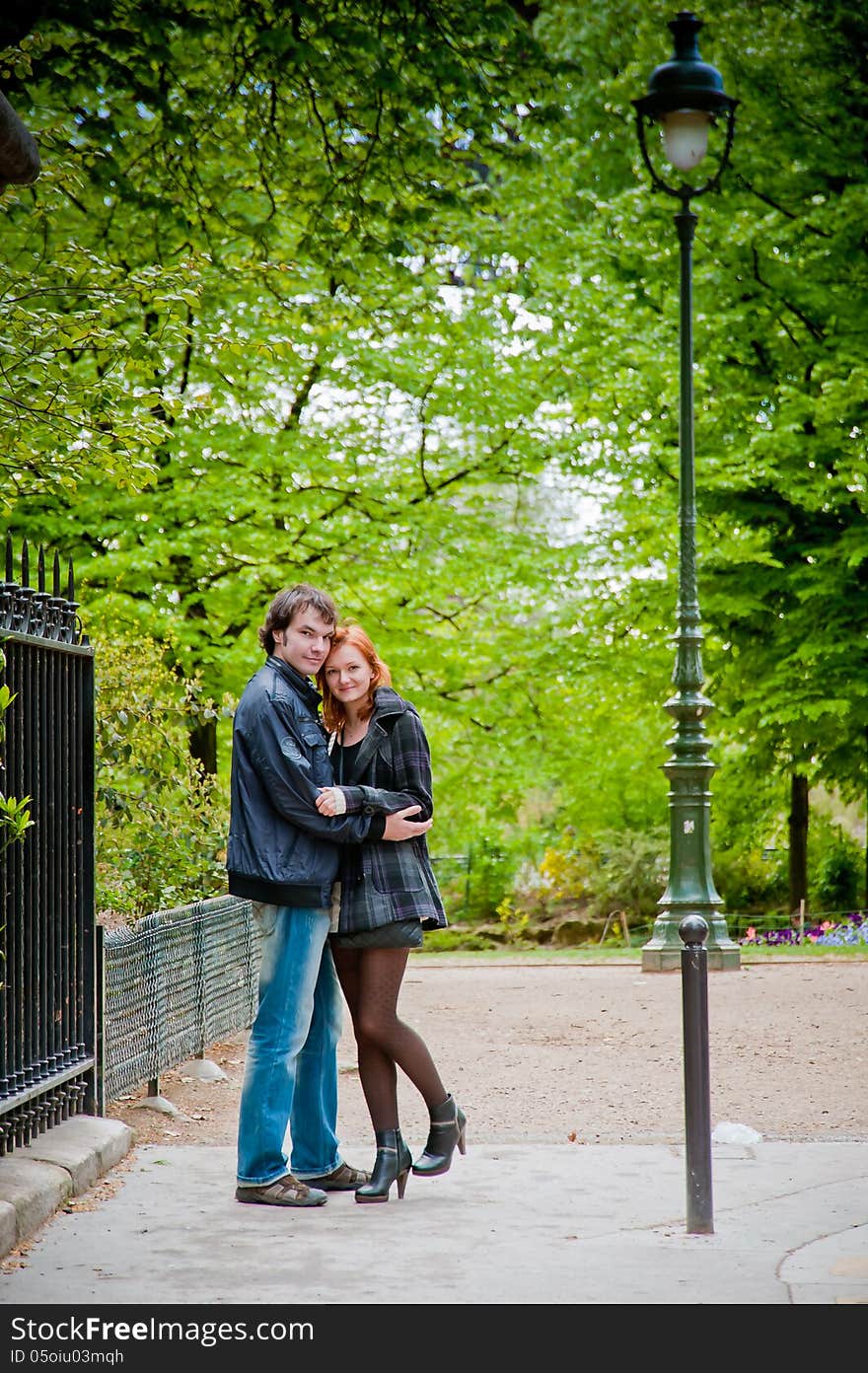 Lovers look at a camera and hugging in Paris in the park near Eiffel Tower. Lovers look at a camera and hugging in Paris in the park near Eiffel Tower