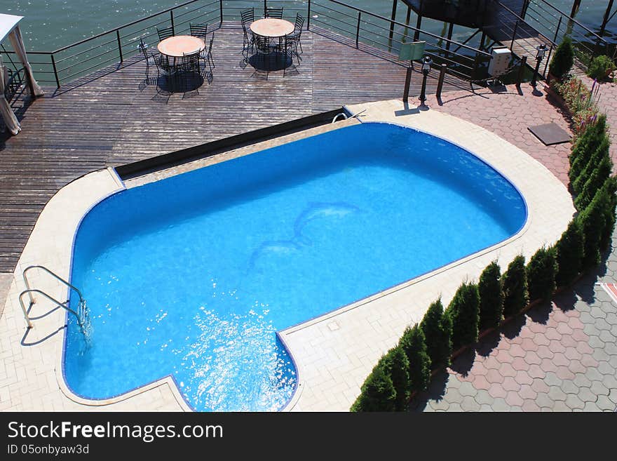 Pool and terace with tables and chairs near lake