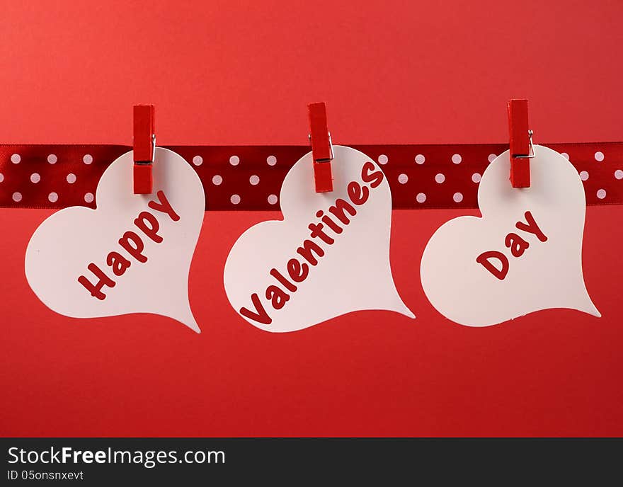 Happy Valentines Day Message Greeting Written Across White Heart Tags Hanging From Red Pegs On A Line