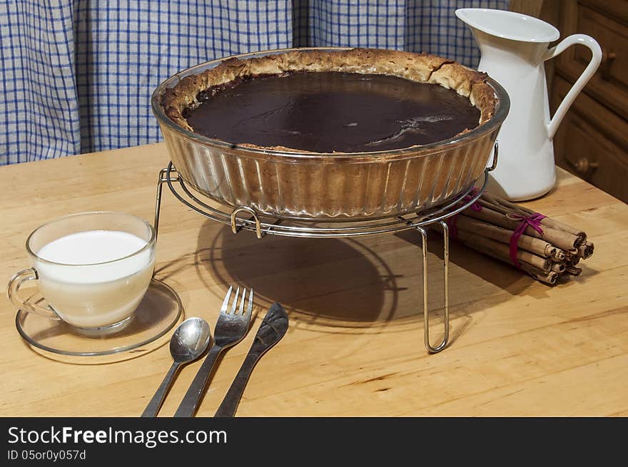 Chocolate cheesecake in a glass baking dish. Near glass cup of milk, cinnamon sticks. Chocolate cheesecake in a glass baking dish. Near glass cup of milk, cinnamon sticks